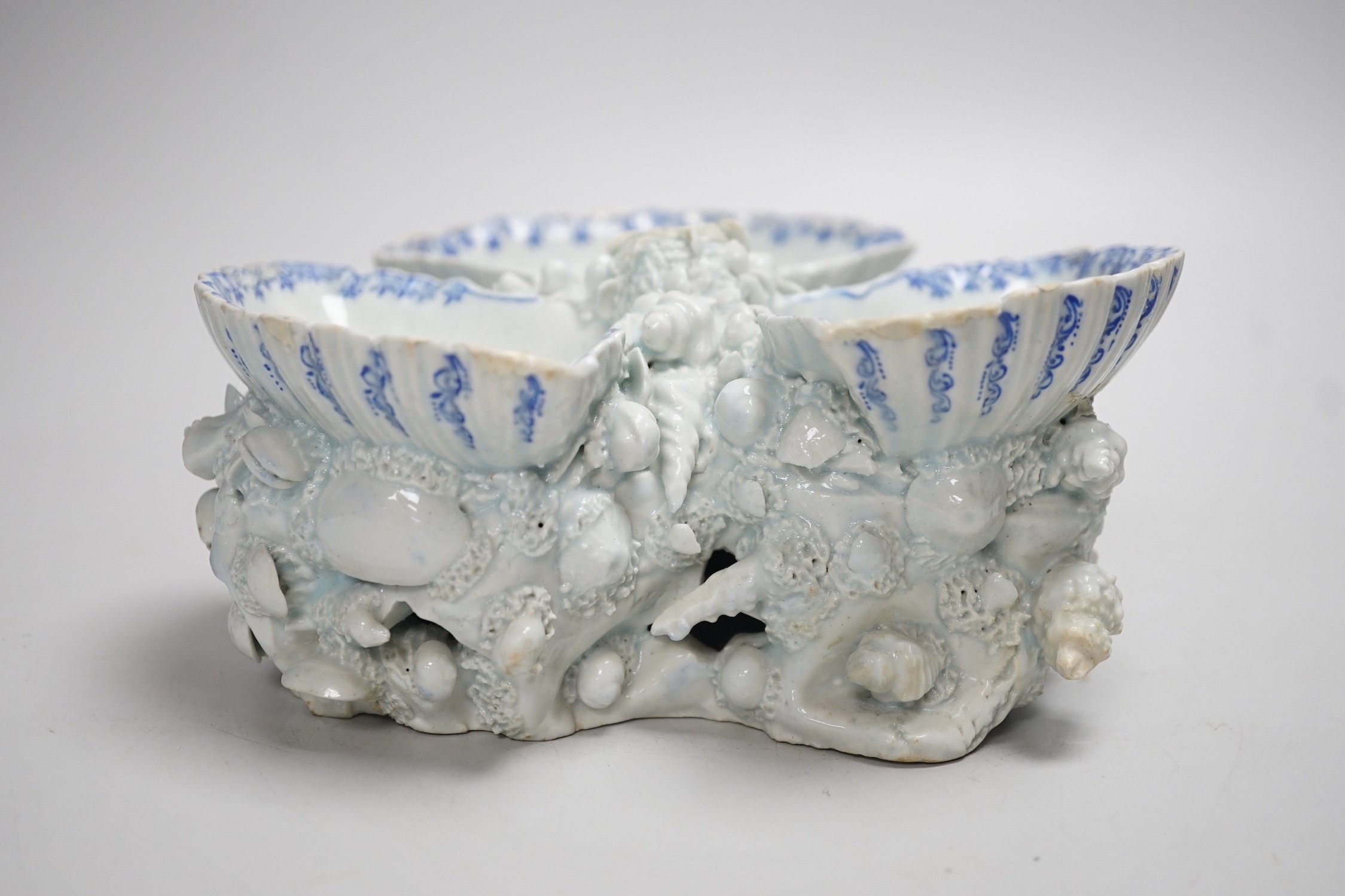 An early Bow porcelain three shell salt, the naturalistically modelled shells picked out in underglaze blue, on a shell and coral encrusted base, 8cm high